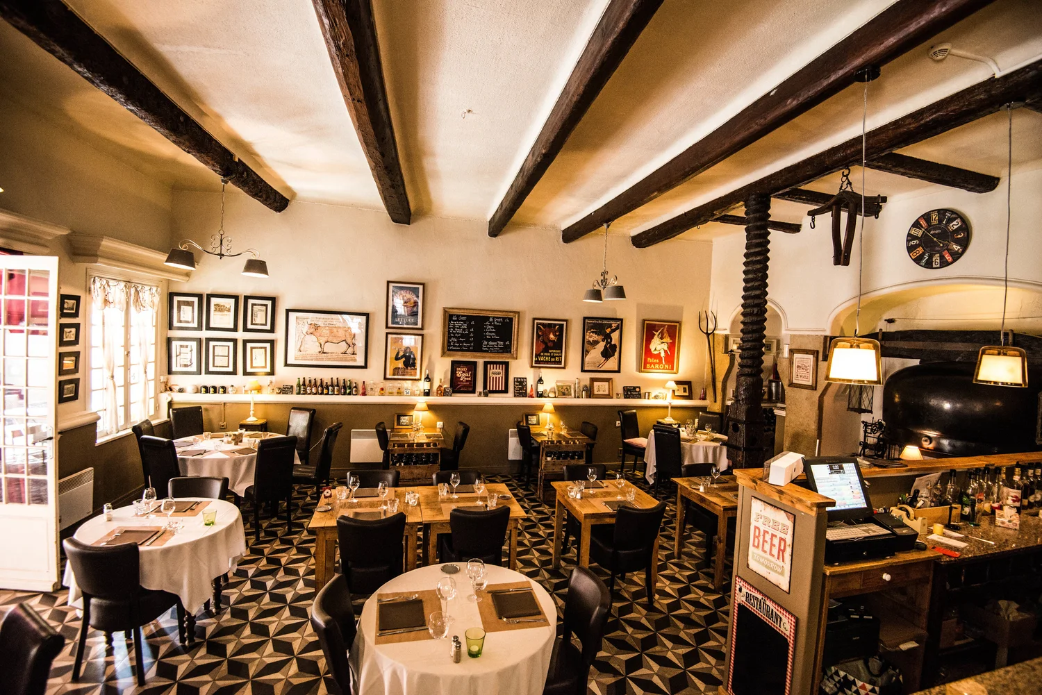 La salle de l'Auberge Provençale : poutres, tables dressées et sol en damier