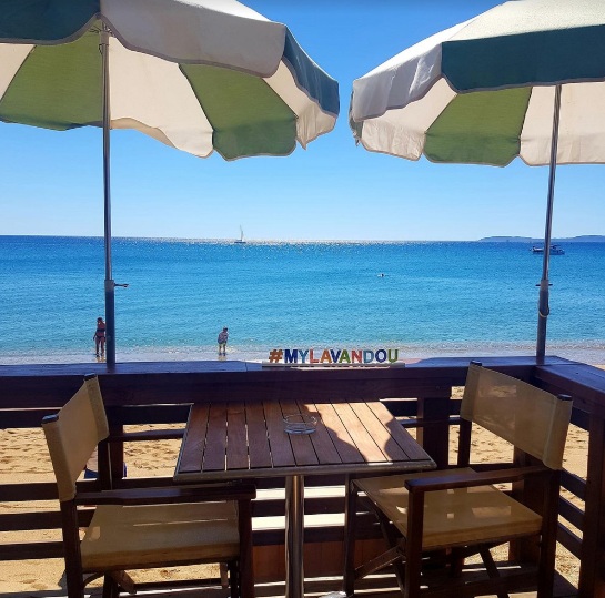 Parasols vert et blanc, tables face à la plage et à la mer turquoise du Lavandou