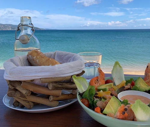 Salade fraîche aux crevettes et avocat, corbeille de pain et carafe d'eau, servie face à la mer turquoise du Lavandou