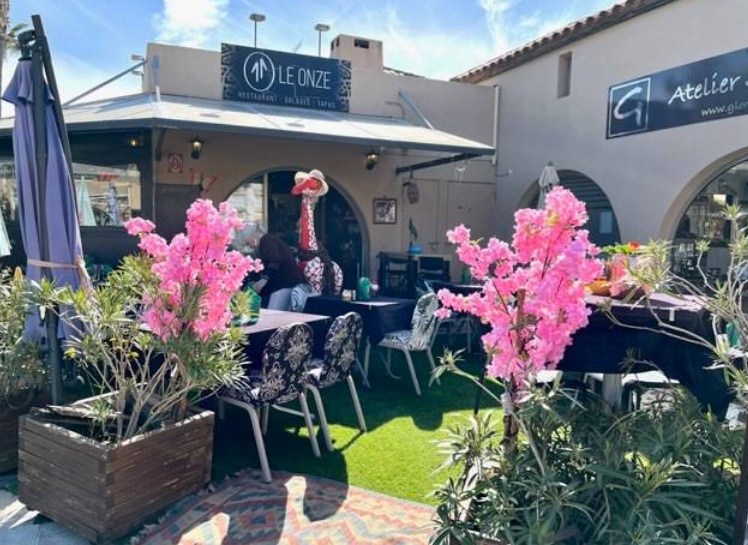 Façade et terrasse du Onze au nouveau port : enseigne Le Onze, fleurs roses et chaises à motifs