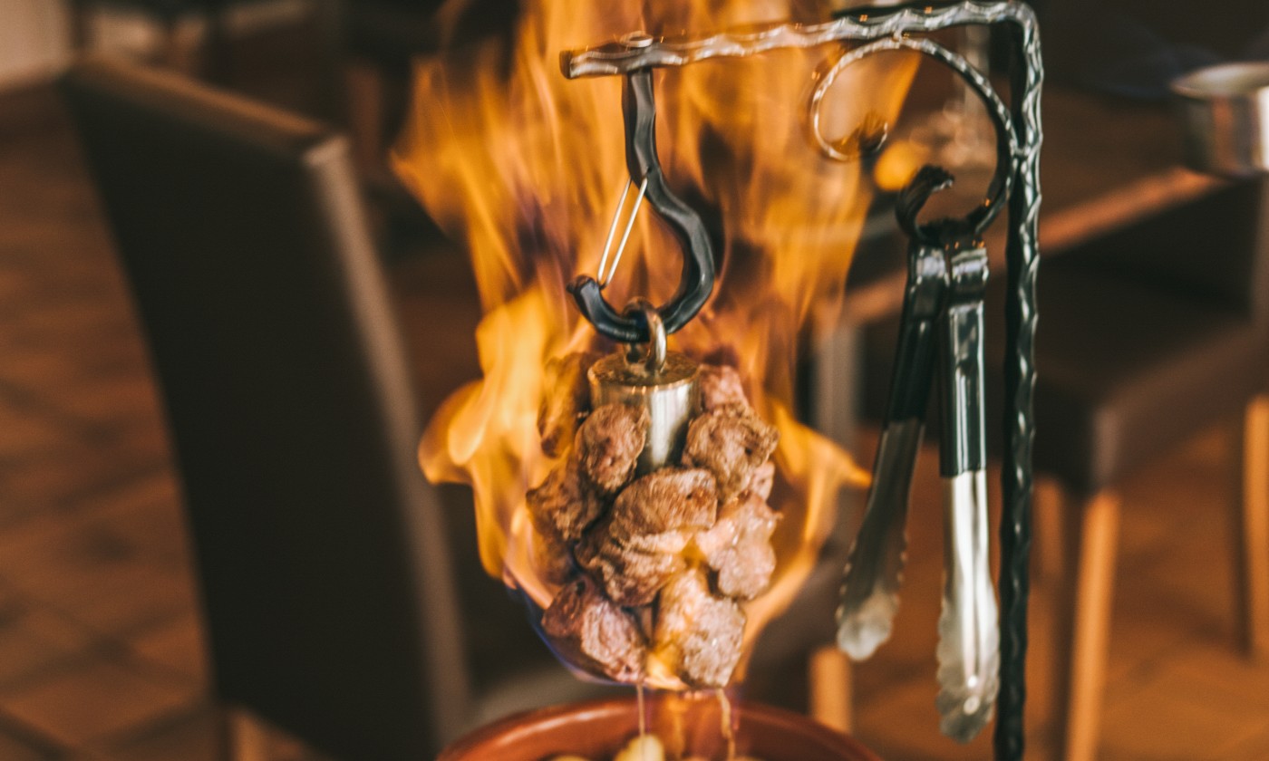 Une potence flambée à L'Emberluque : brochette de bœuf suspendue à un crochet en fer forgé, léchée par les flammes du cognac