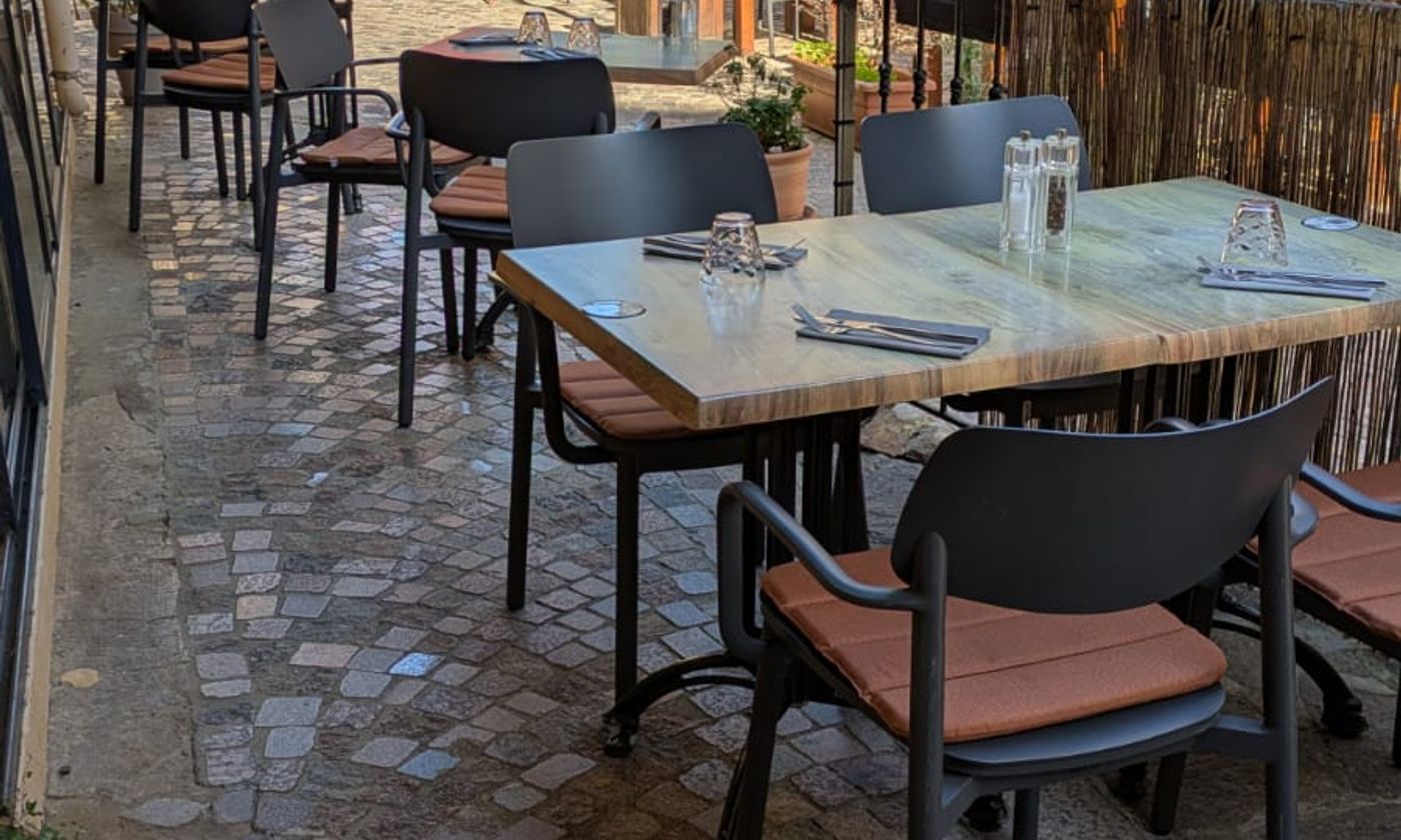 Tables dressées sur les pavés en fin d'après-midi, lumière dorée sur la ruelle