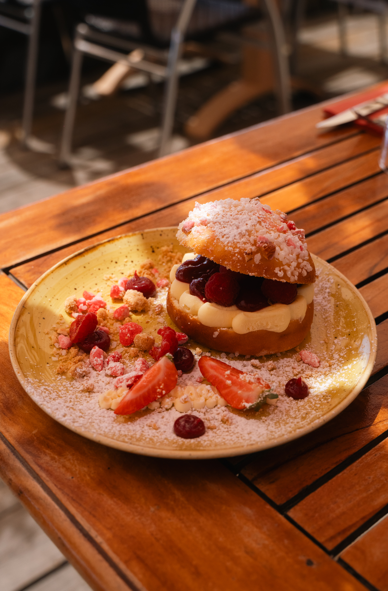 La tarte tropézienne aux framboises de Noca Plage, saupoudrée de sucre, sur assiette dorée