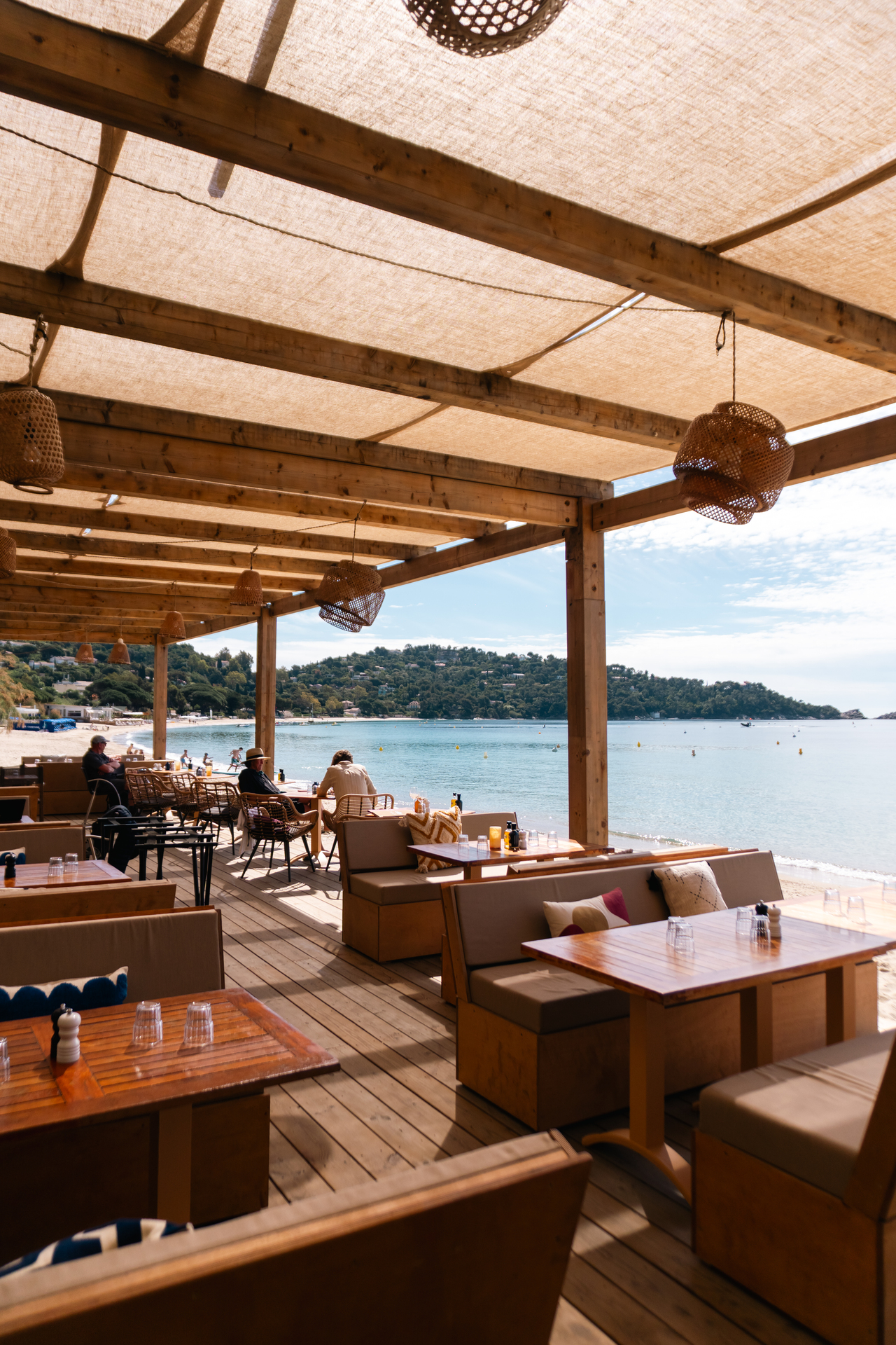 Salon lounge de Noca Plage sous la pergola, banquettes et vue directe sur la mer de Cavalière