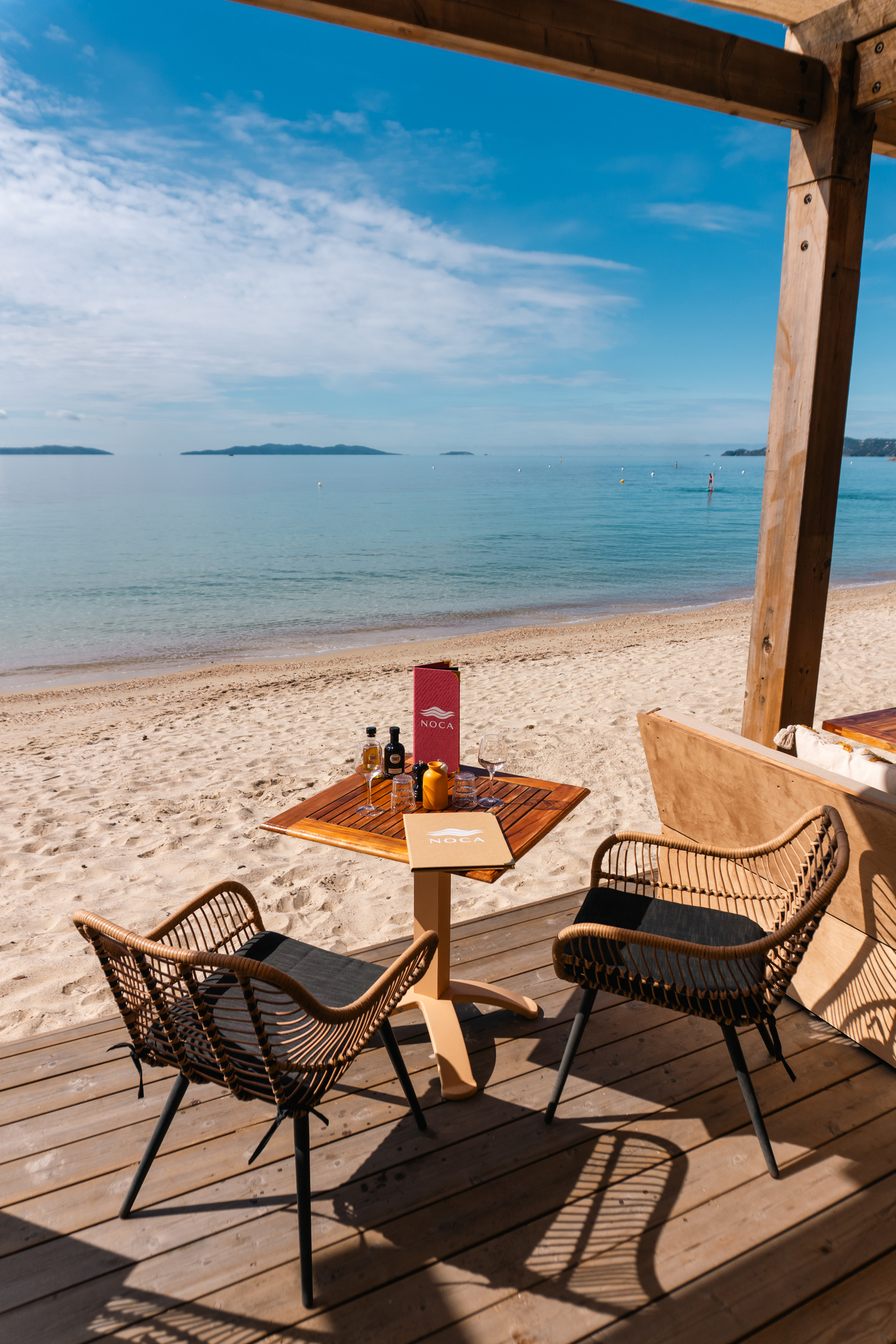 La terrasse de Noca Plage au bord du sable de Cavalière : deux fauteuils face à la mer turquoise et aux îles d'Or