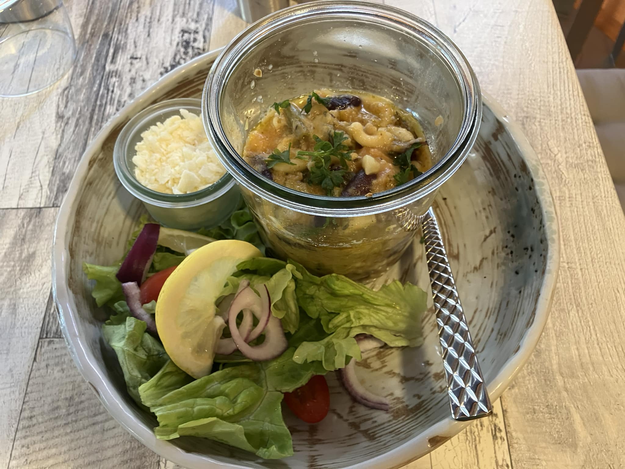 Soupe au pistou servie dans un bocal en verre avec salade fraîche et parmesan râpé