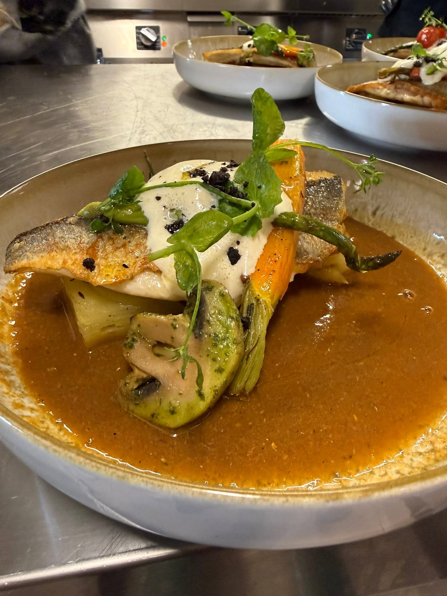 Plat de poisson et fruits de mer en bouillon thaï crémeux, riz et citron vert, terrasse sur la mer