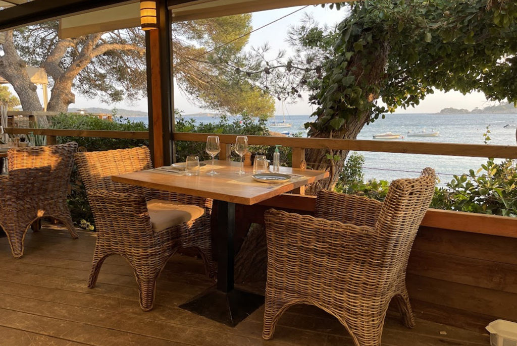 Table en rotin sur la terrasse, vue mer entre les pins